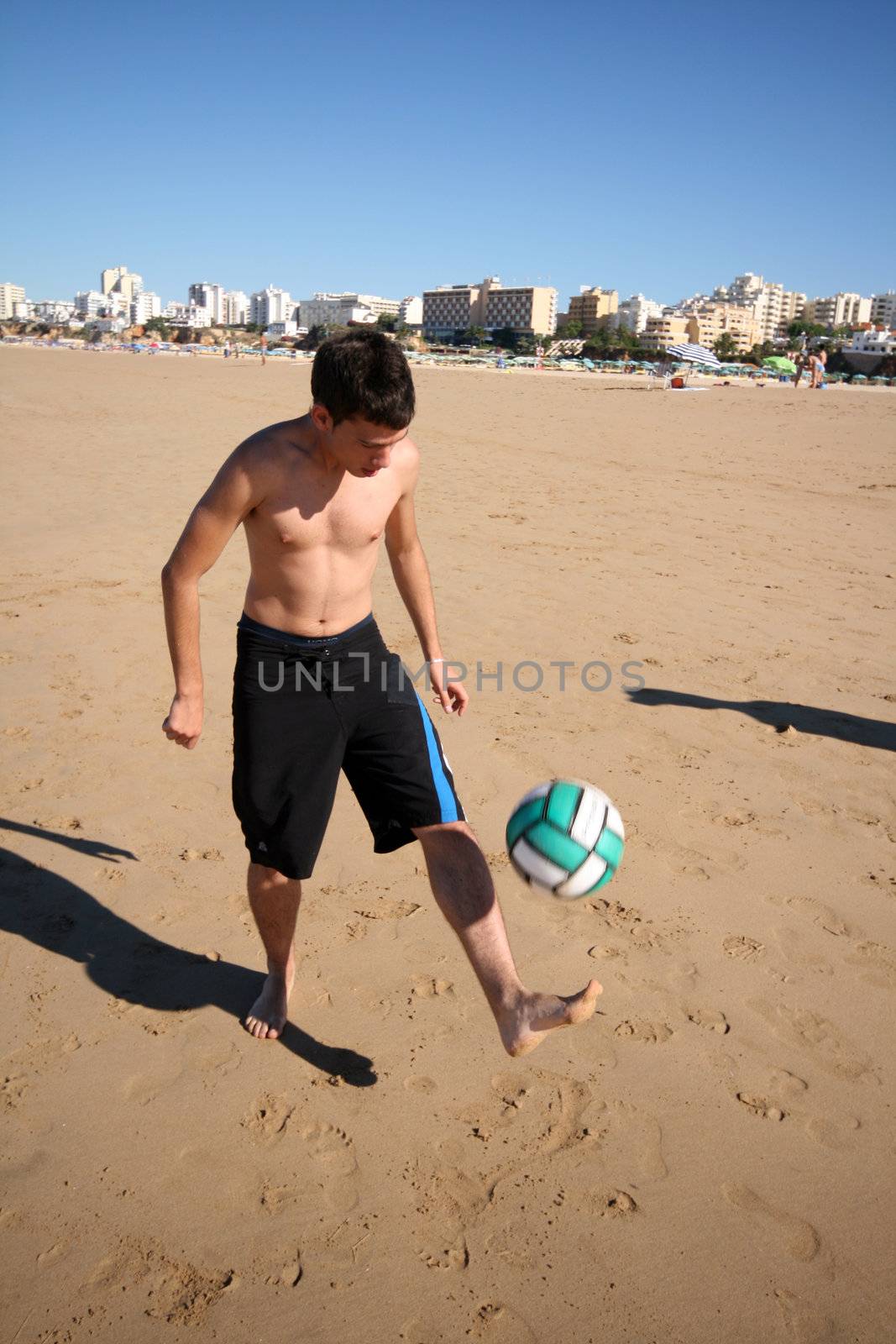 young man playing beach soccer