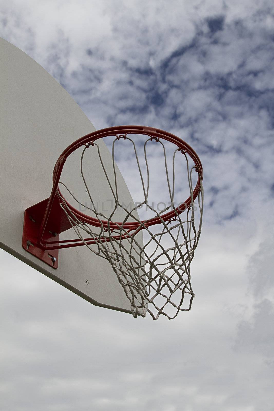 Close up shoot of a basketball hoop against a clouded blue sky