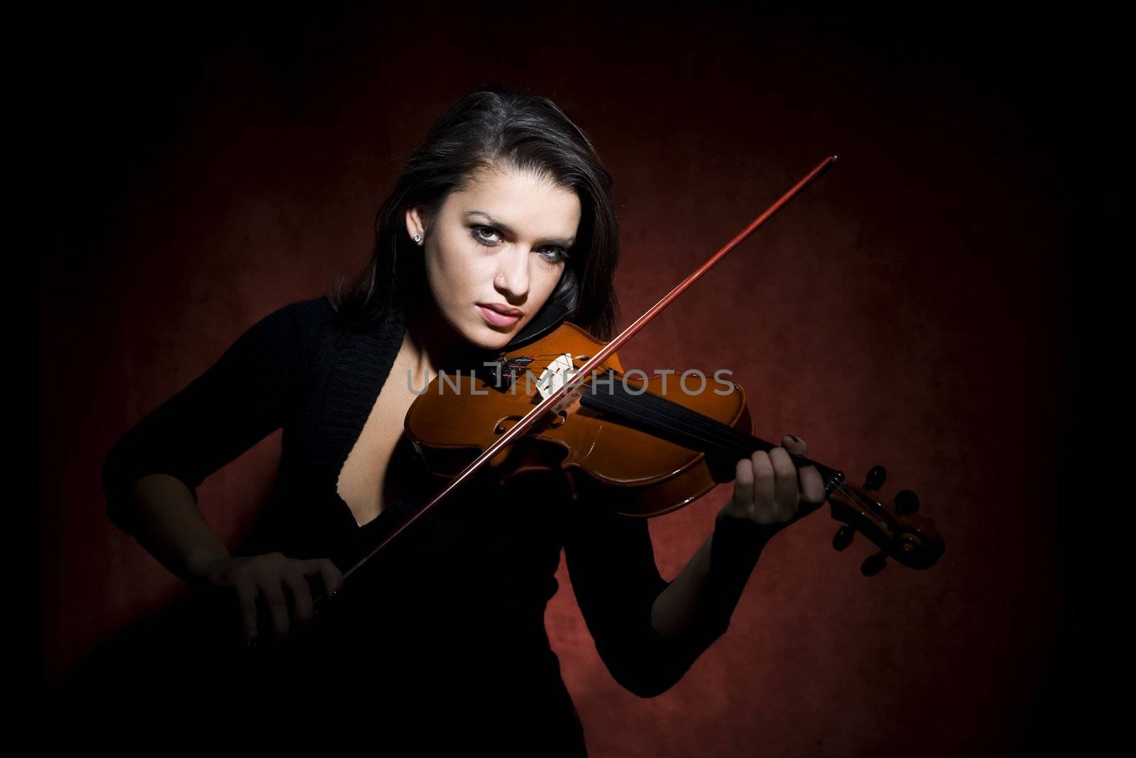 Pretty Hispanic woman in studio playing a violin