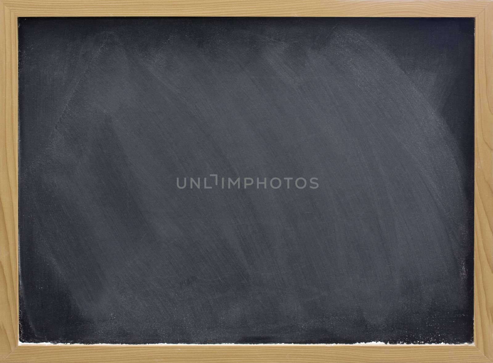 blank blackboard in wooden frame with white chalk dust and eraser smudges