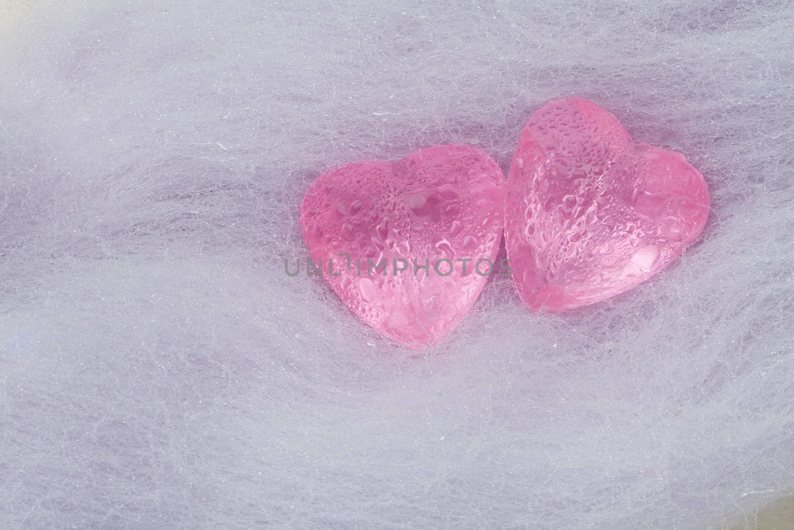 Two pink crystal hearts lie on the wool