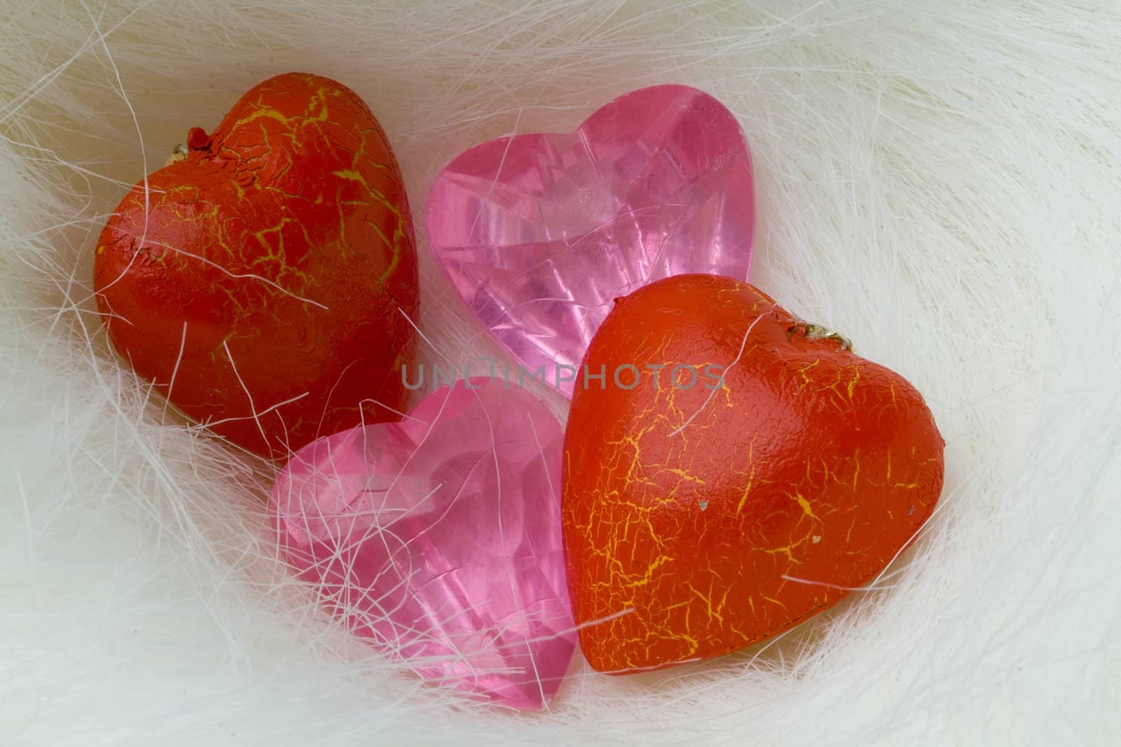 Two red wood hearts and two pink crystal hearts lie on the fur