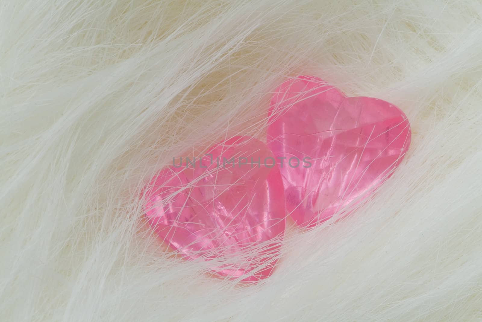 Two pink crystal hearts lie on the fur