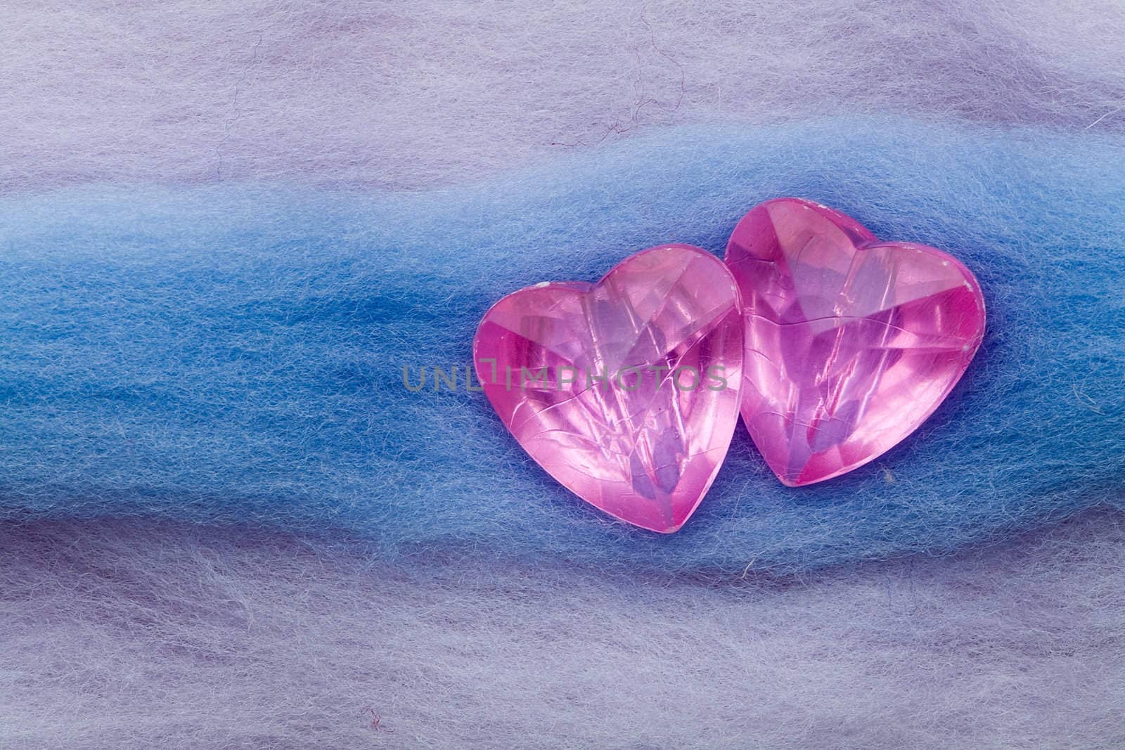 Two pink crystal hearts on the white and blue wool