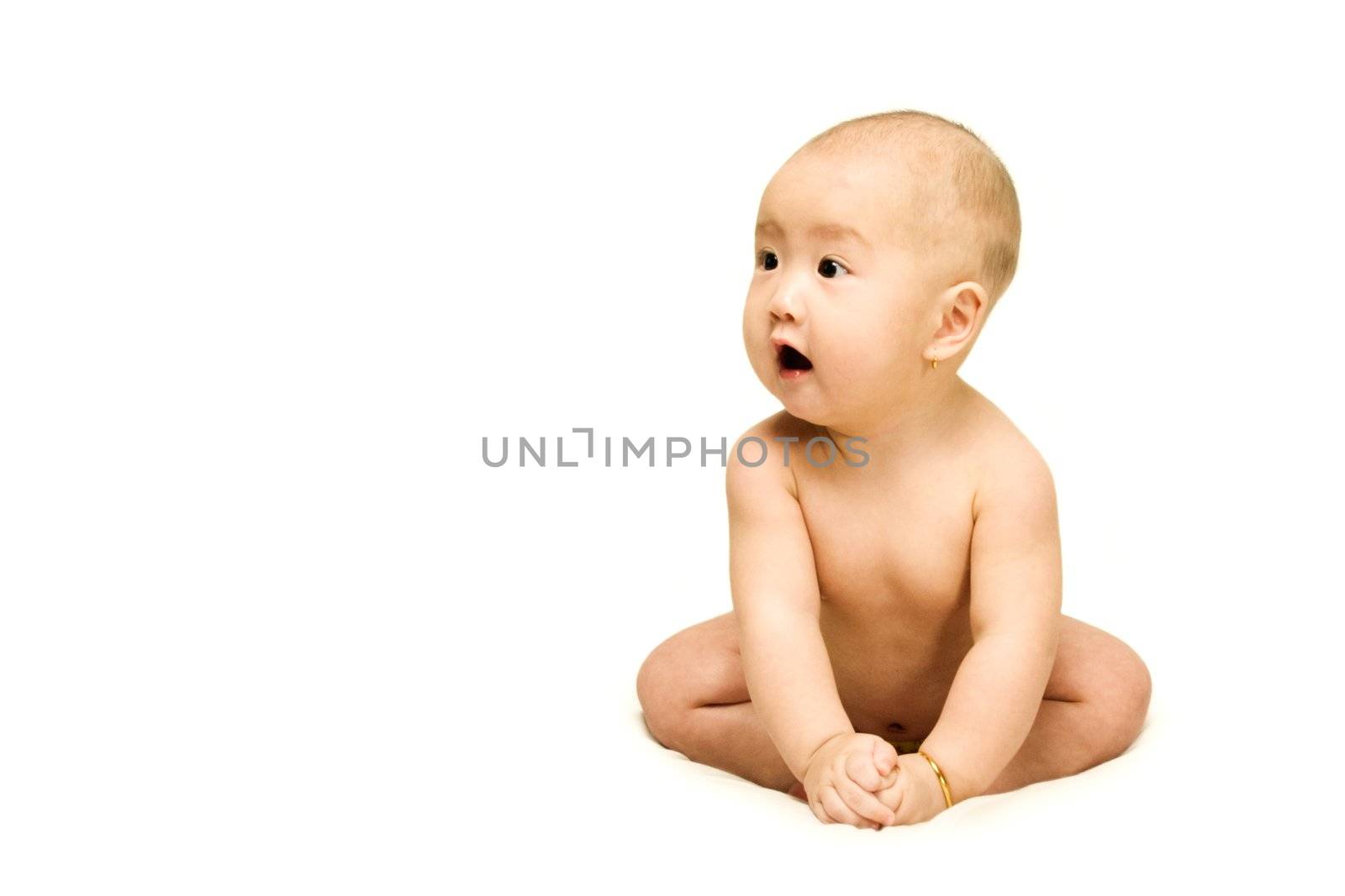 A naked 6 months old baby is sitting alone