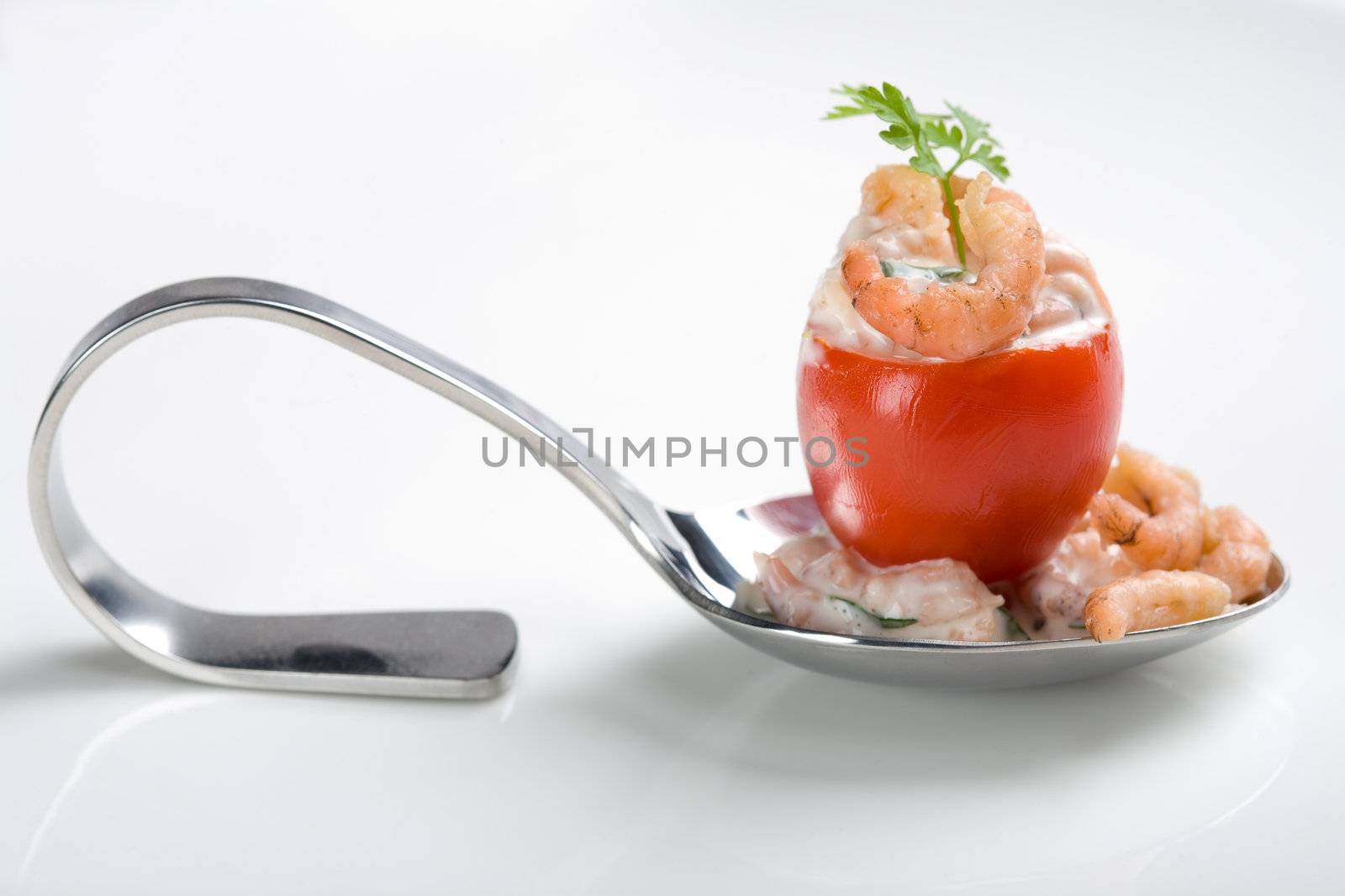 Small cherry tomatoe filled with shrimp cocktail on a spoon