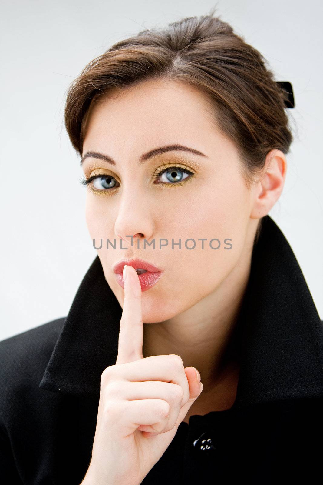 Face of a beautiful blue eyed brunette saying shhhhh, isolated