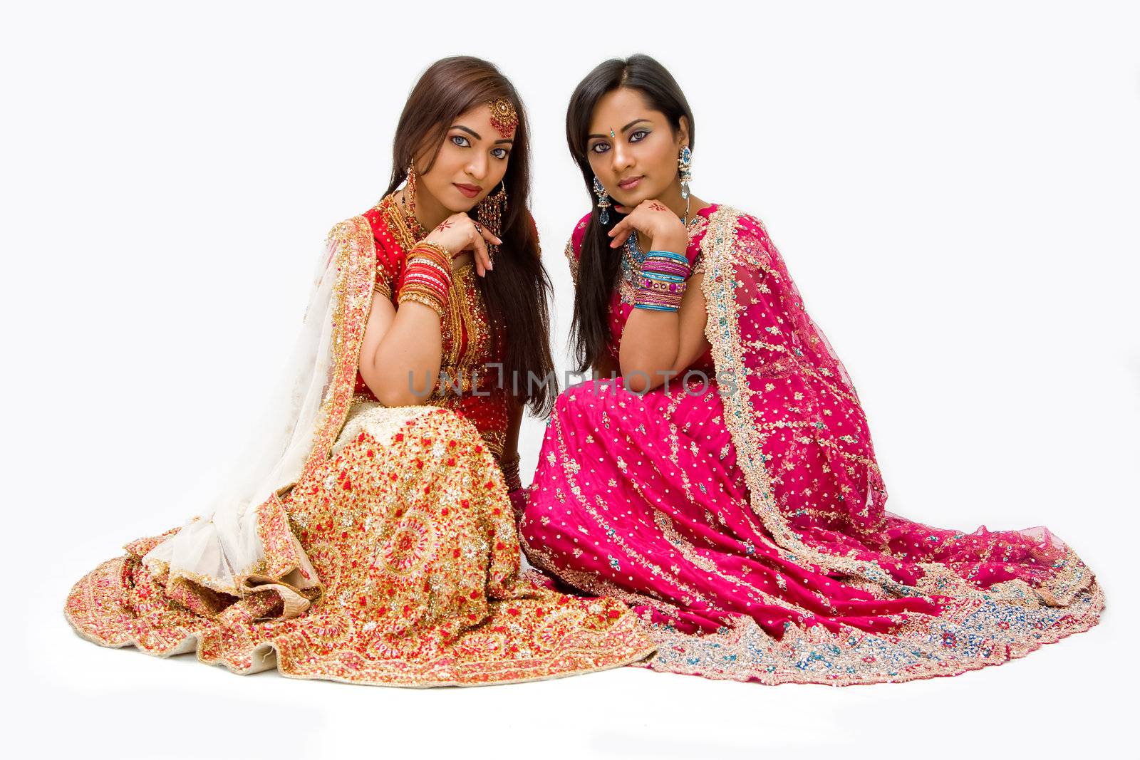 Two beautiful harem girls or belly dancers or Hindu brides sitting, isolated