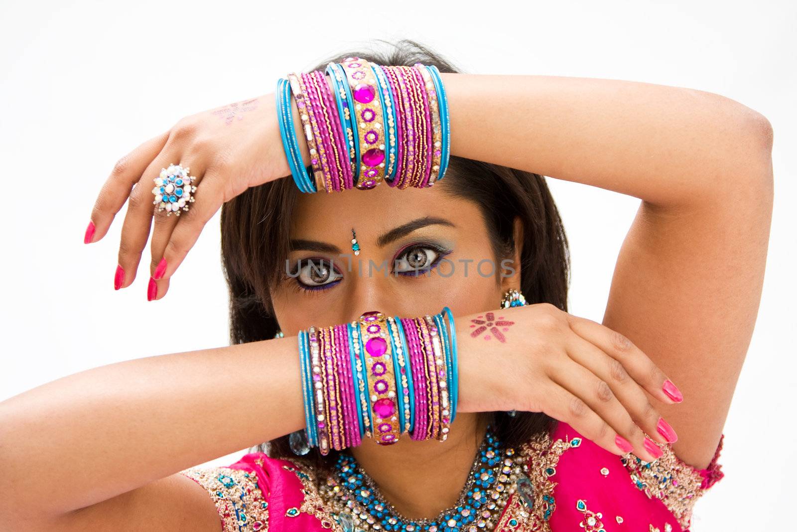 Beautiful face of a Bengali bride with her arms across her head covered with colorful bracelets, isolated