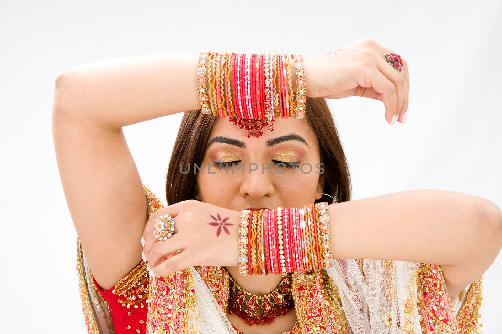 Beautiful face of a Bengali bride with her arms across her head covered with colorful bracelets and eyes closed, isolated