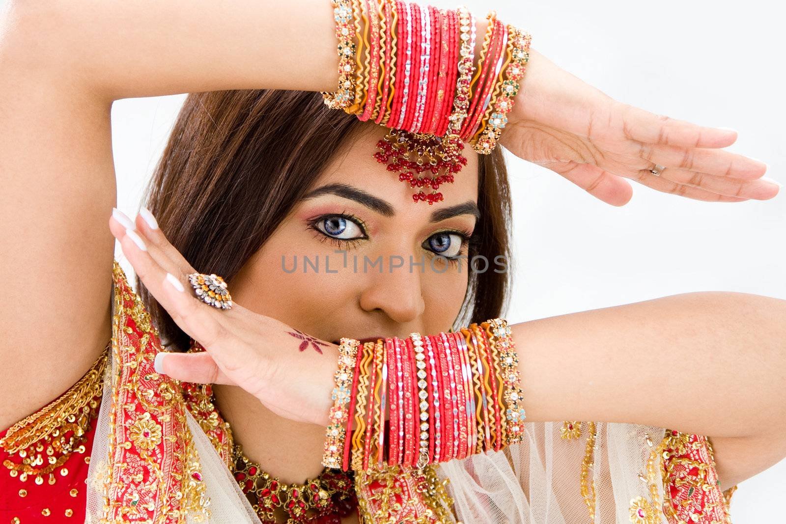 Beautiful face of a Bengali bride with her arms across her head covered with colorful bracelets, isolated