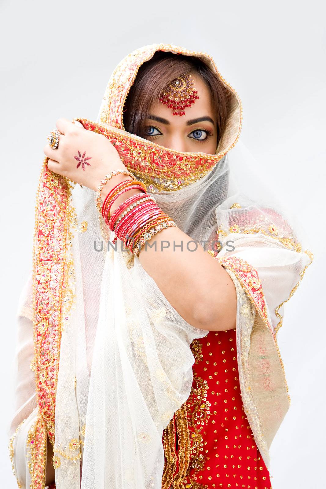 Elegant Bengali bride with veil in front of mouth, isolated