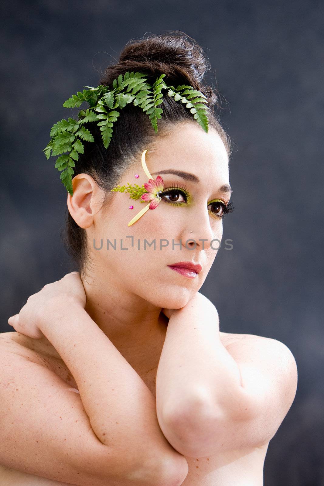 Beautiful brunette face with pink green yellow eye flower petal makeup, isolated on gray