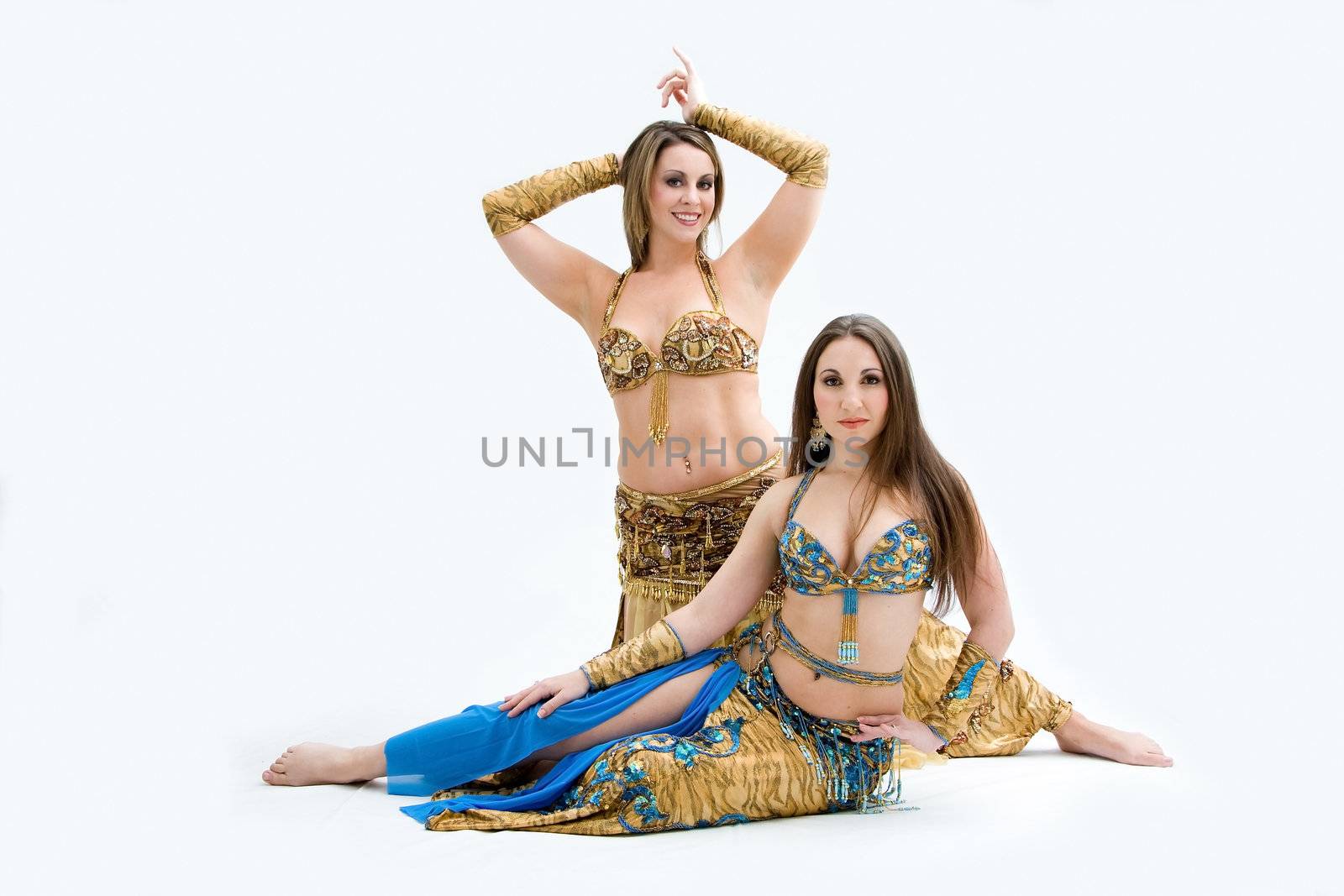 Two beautiful belly dancers dressed in gold and blue, isolated