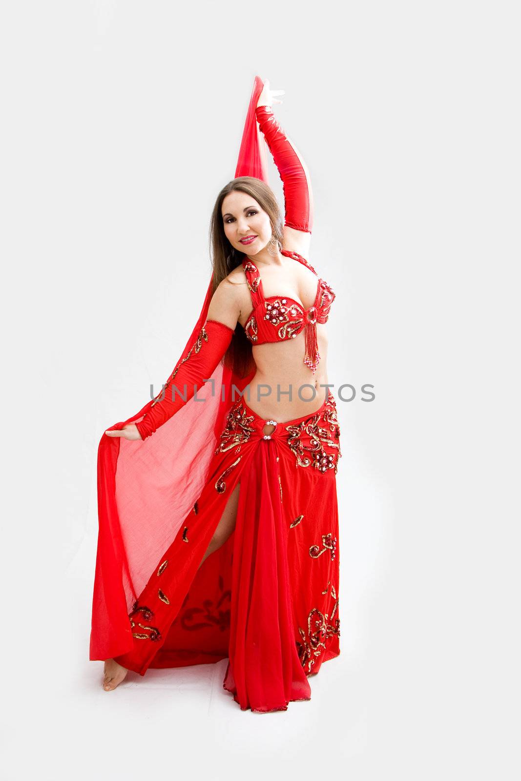 Beautiful belly dancer in red outfit holding veil, isolated
