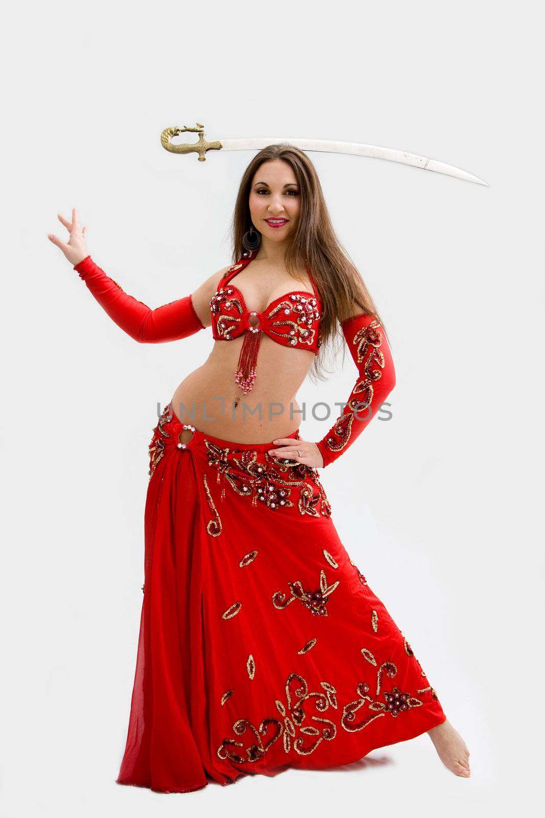 Beautiful belly dancer in red outfit with sword on her head, isolated