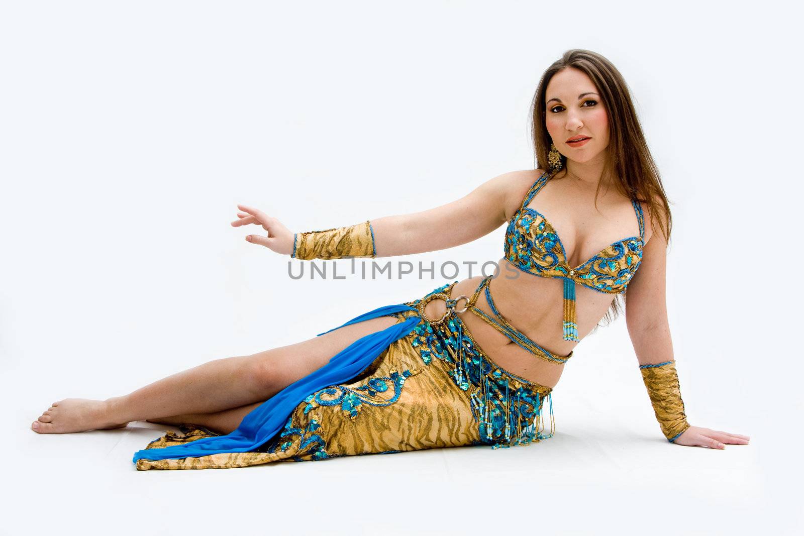 Beautiful belly dancer in blue outfit laying on floor, isolated