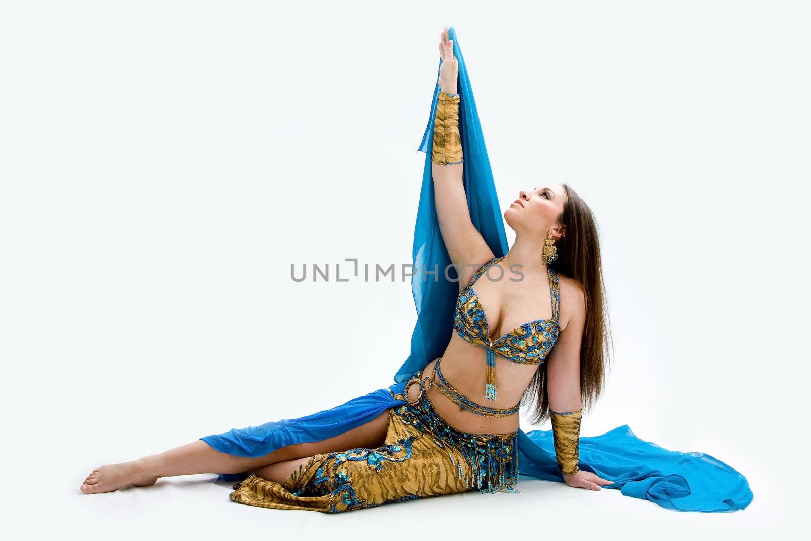 Beautiful belly dancer in blue outfit laying on floor, isolated