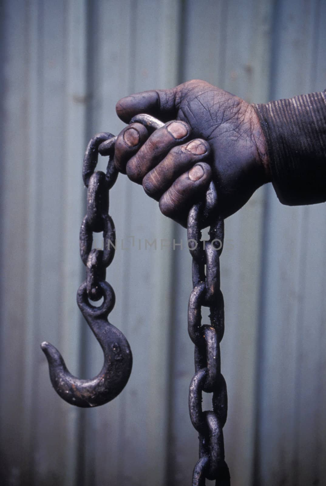 Workers hand holding a chain and hook