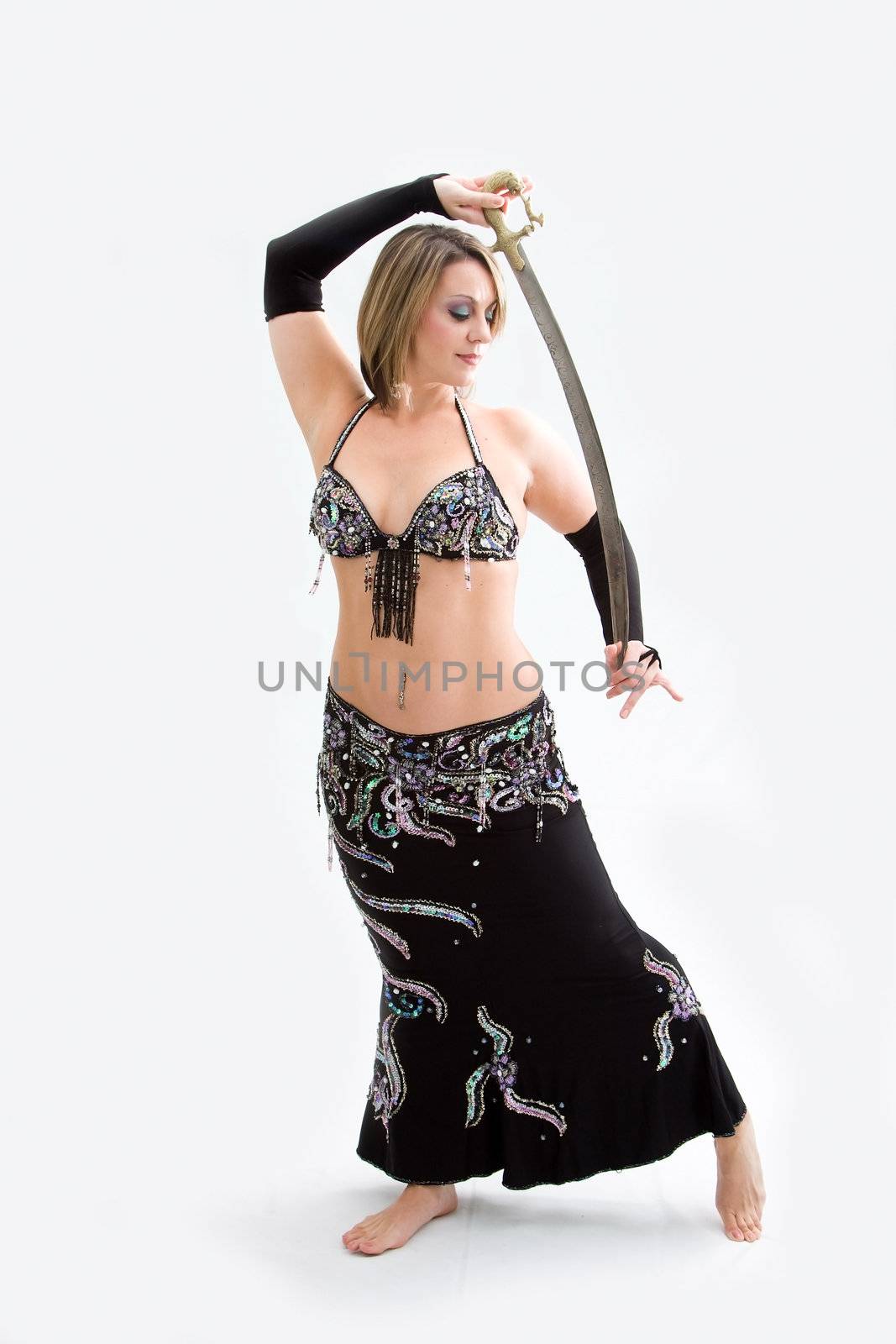 Beautiful belly dancer in black outfit holding sword, isolated