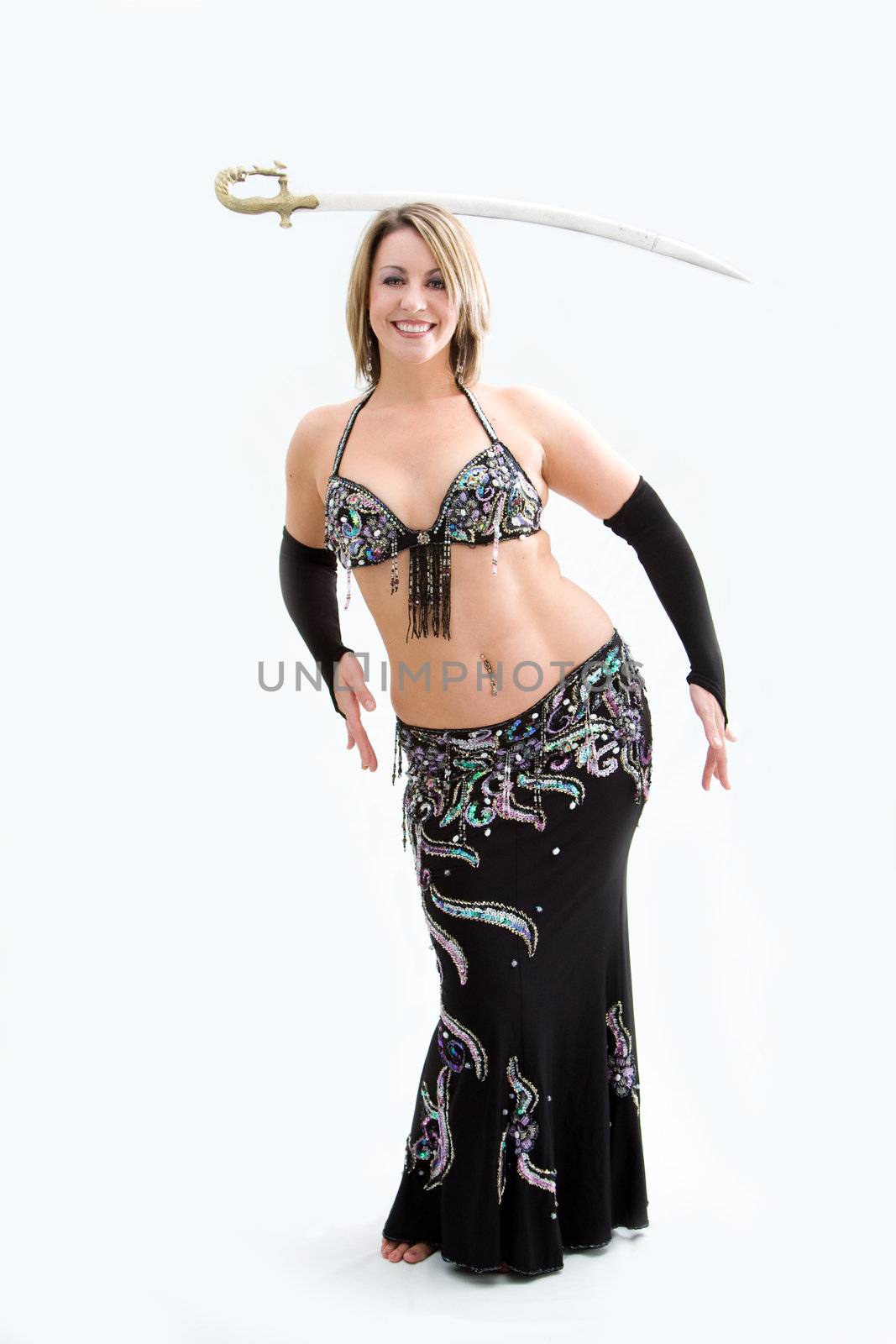 Beautiful belly dancer in black outfit balancing sword, isolated