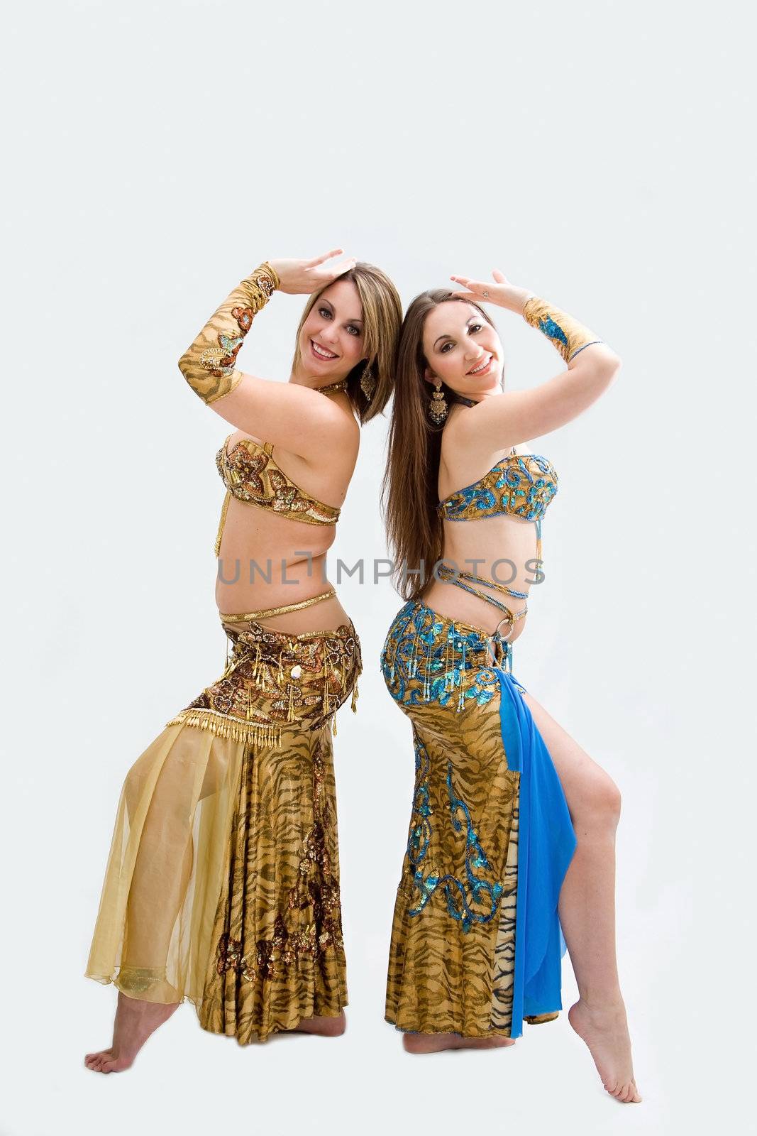 Two beautiful belly dancers dressed in gold and blue, isolated