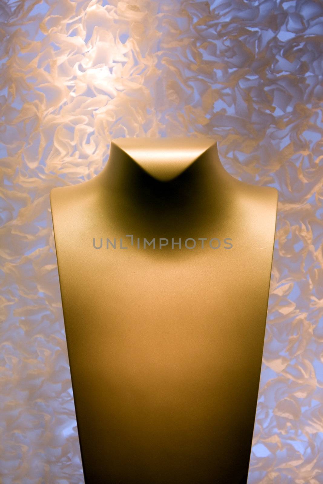 A golden yellow color neck form for display of necklace jewelry on a fluffy background