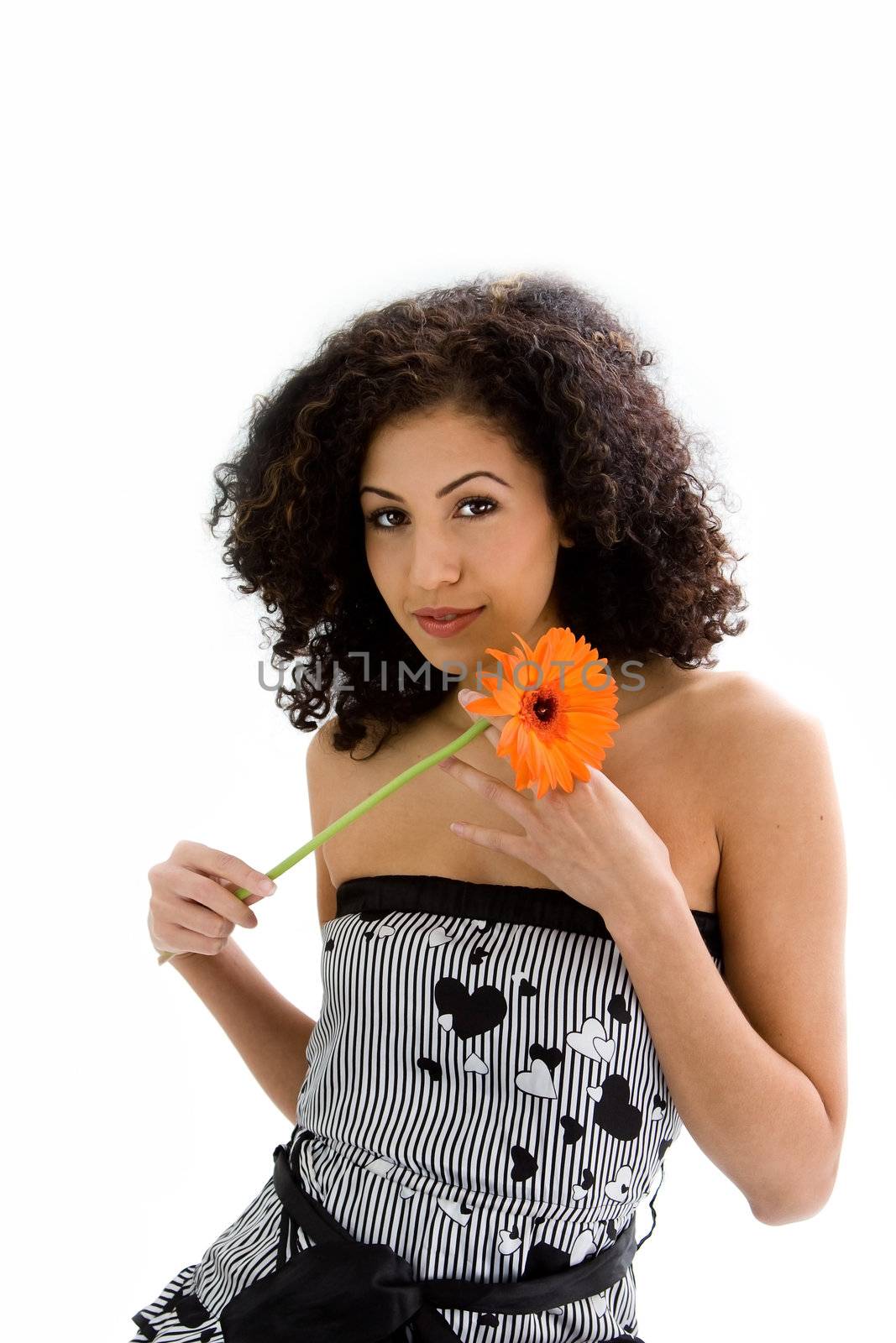 Beautiful young woman with brown curly wild hair and orange flower in hand, isolated