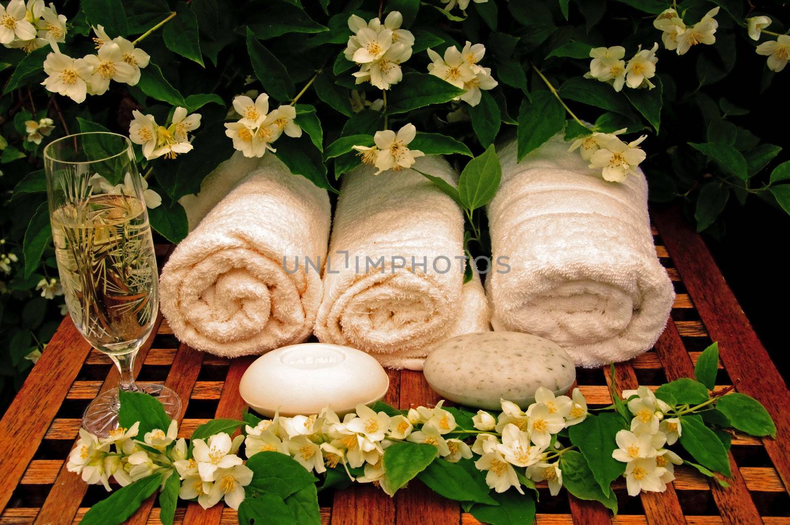 Towels, soap, flowers and a glass of white vine on a table
