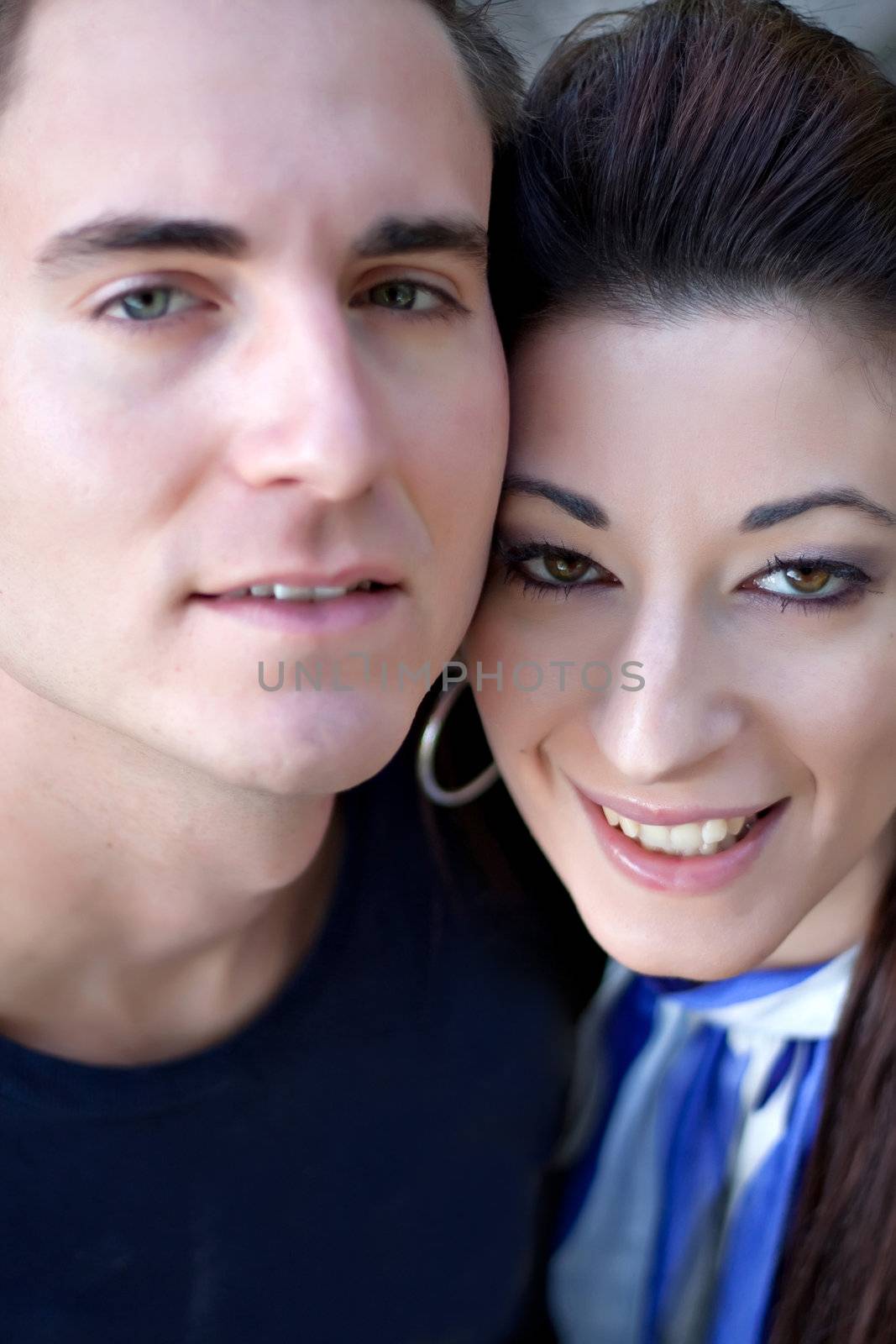 A happy young couple in their mid 20s smiling with their heads close together. Shallow depth of field with sharpest focus on the woman.