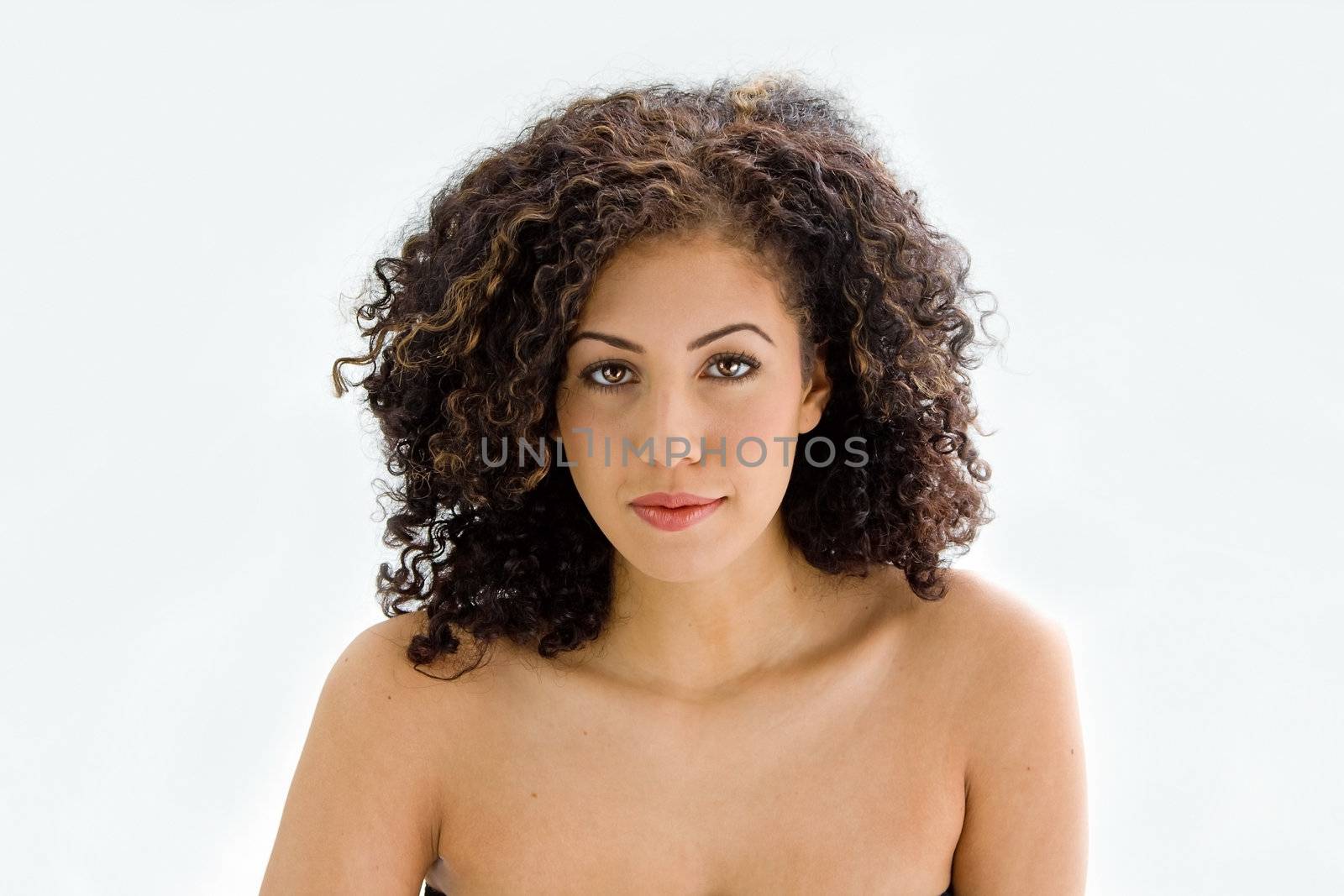 Sincere beautiful young woman with brown curly wild hair and bare shoulders, isolated