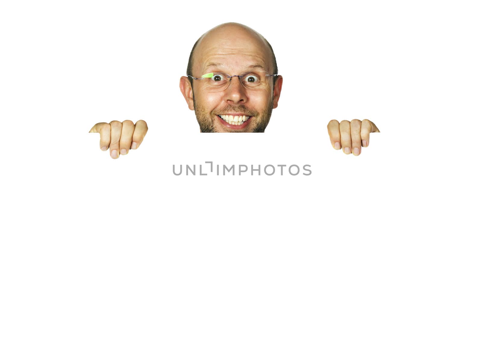 A funny happy smiling man holding a white sign or looking up from behind white wall