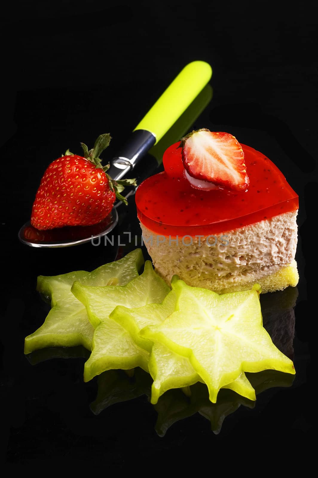 heart shaped strawberry cake dith star fruit or carambola decoration over black reflective backgound