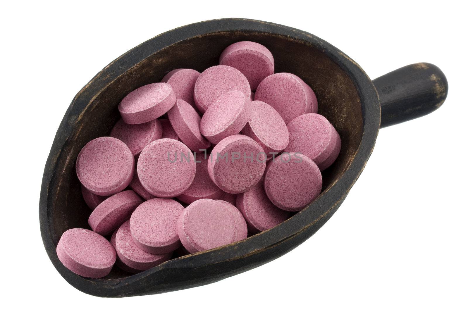 pink pills (tablets) of vitamin, dietary supplement or stomach medicine on a rustic, wooden scoop, isolated on white