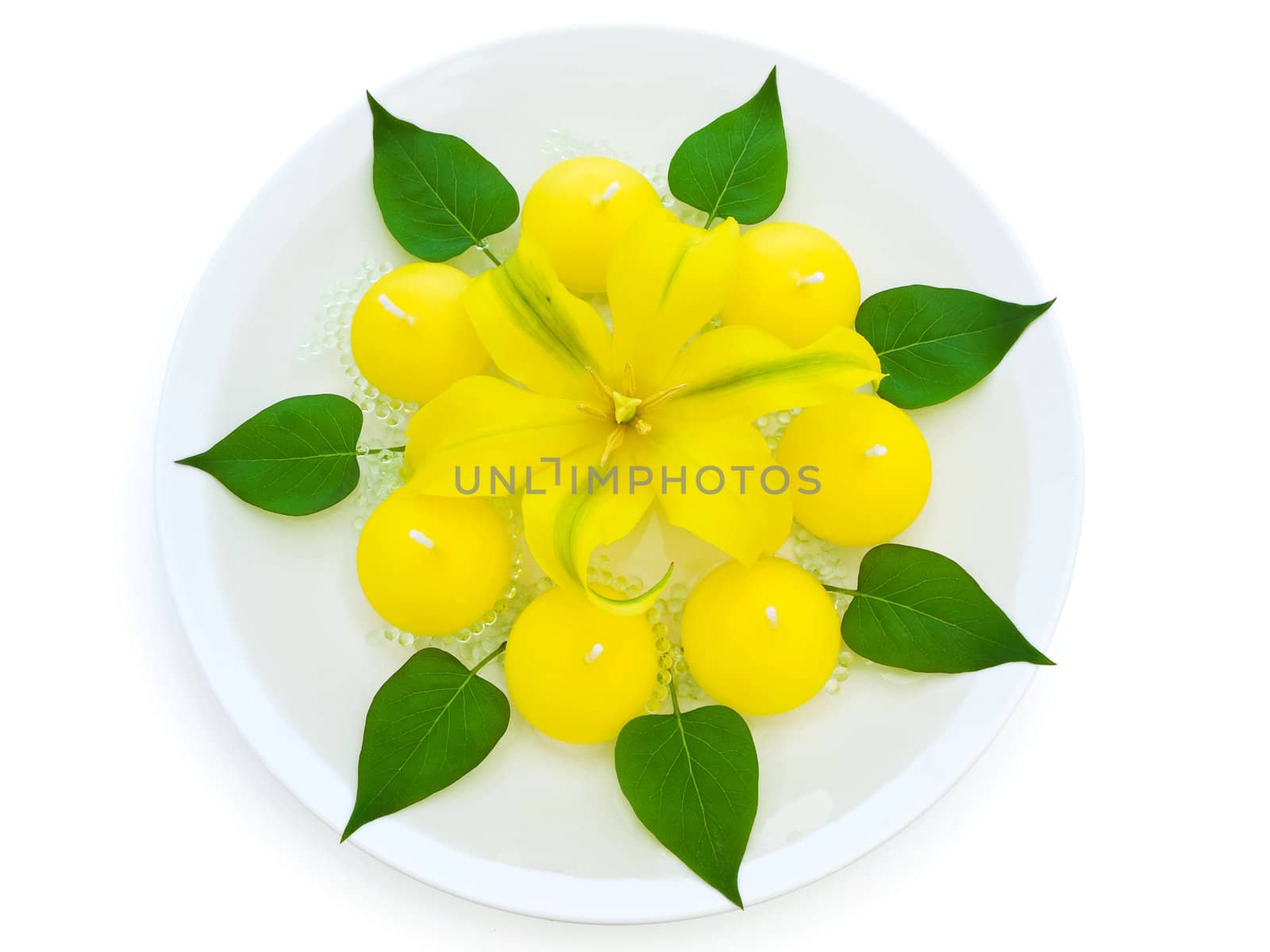 floral spa decoration with lily, candles and green leaves over white background