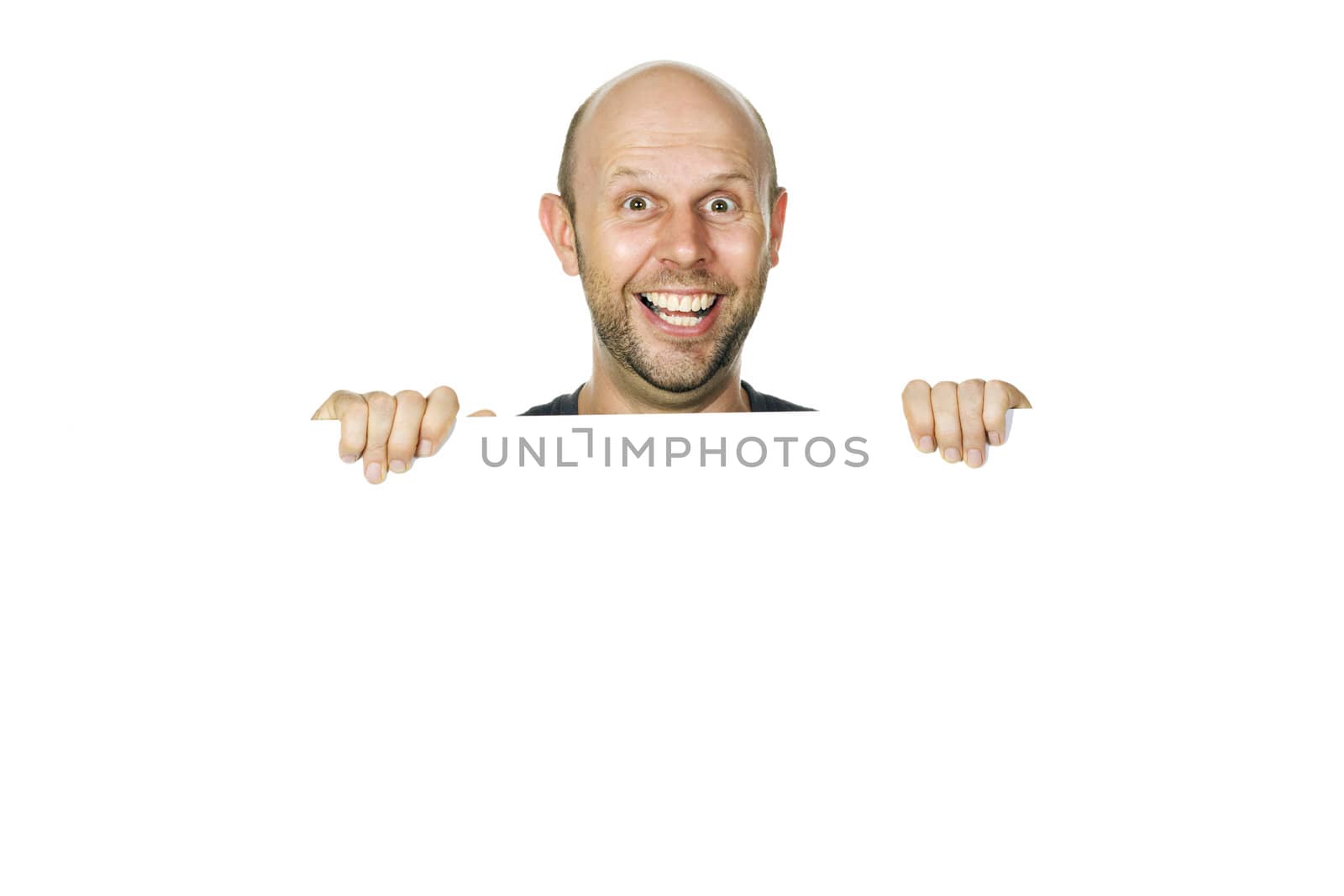 A great portrait of a happy and funny man peeking over a white wall or white sign smiling. Isolated over white.