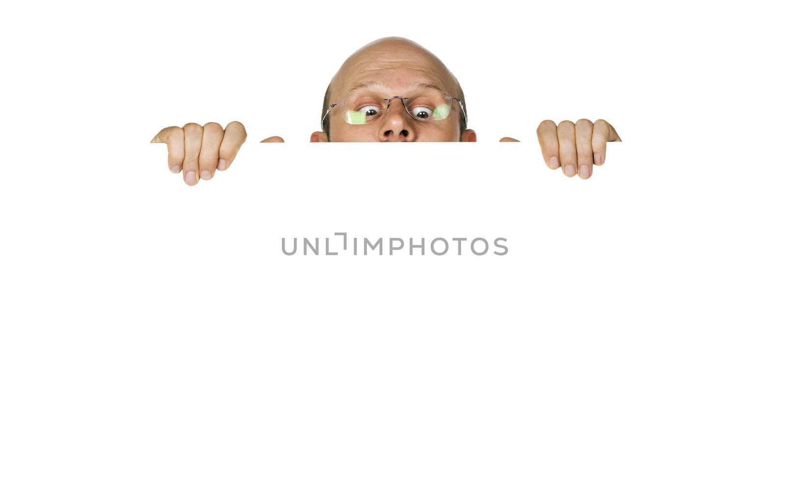 Funny portrait of curious man looking over white wall or sign. Isolated over white.