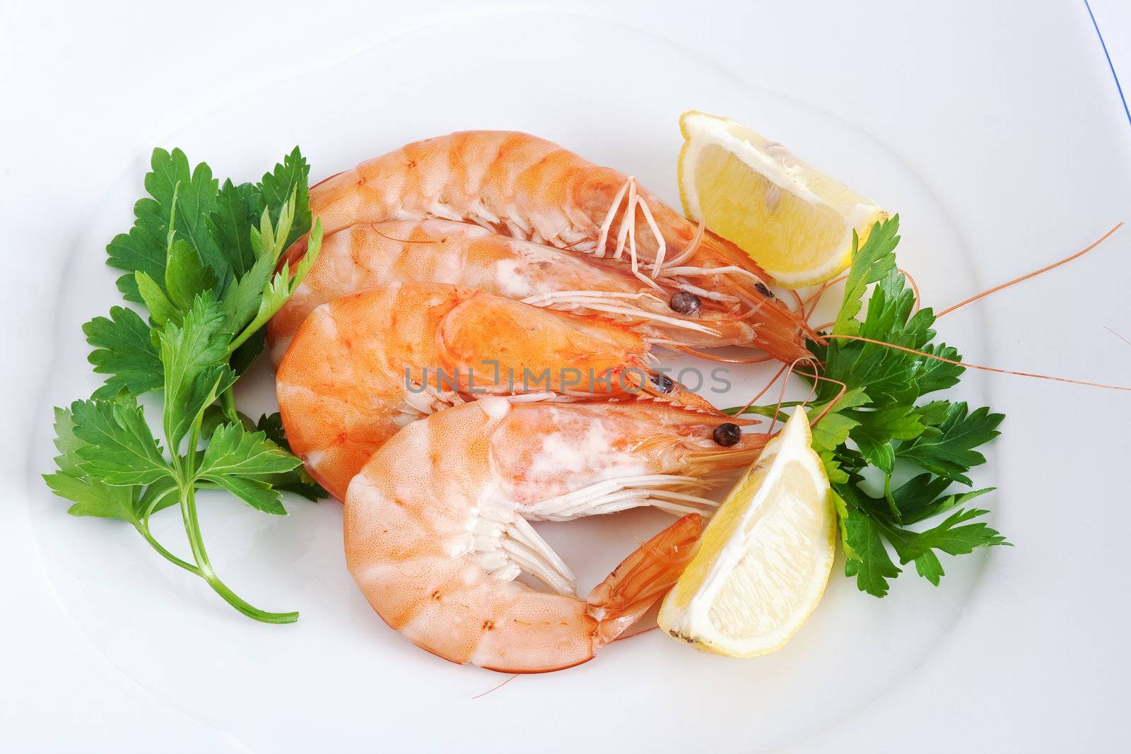 three raw prawns with lemon and parsley on a white plate isolated with clipping path