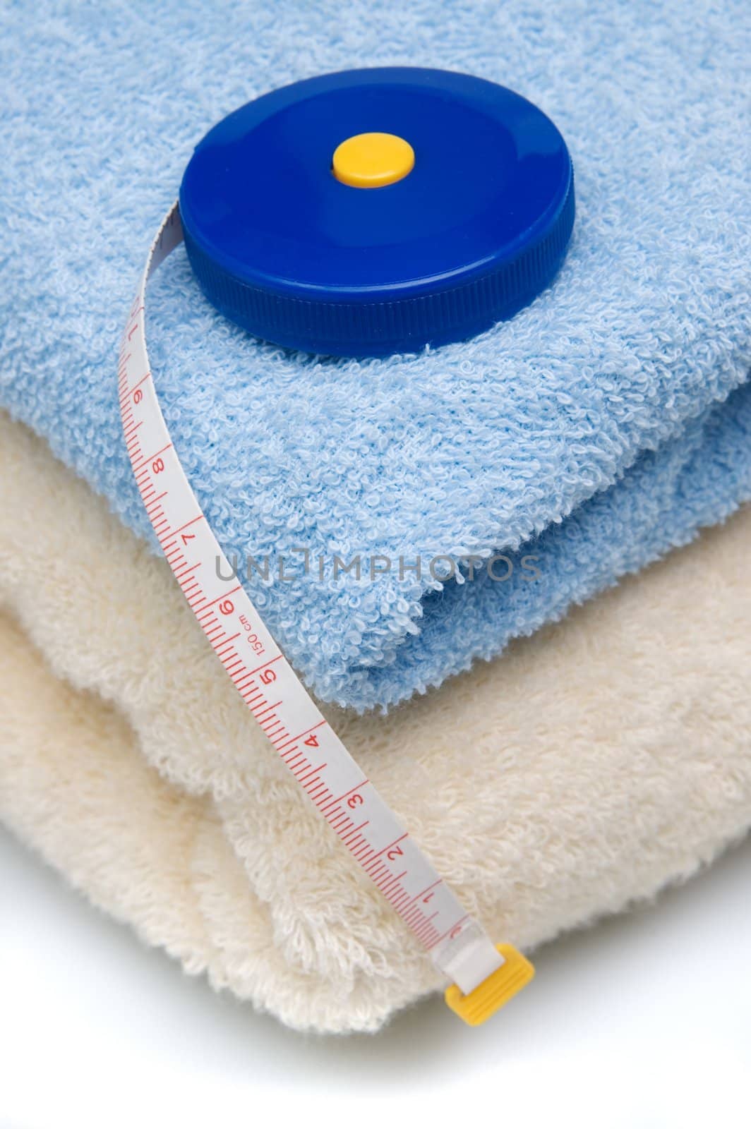 Pile of towels and tape measure, white background