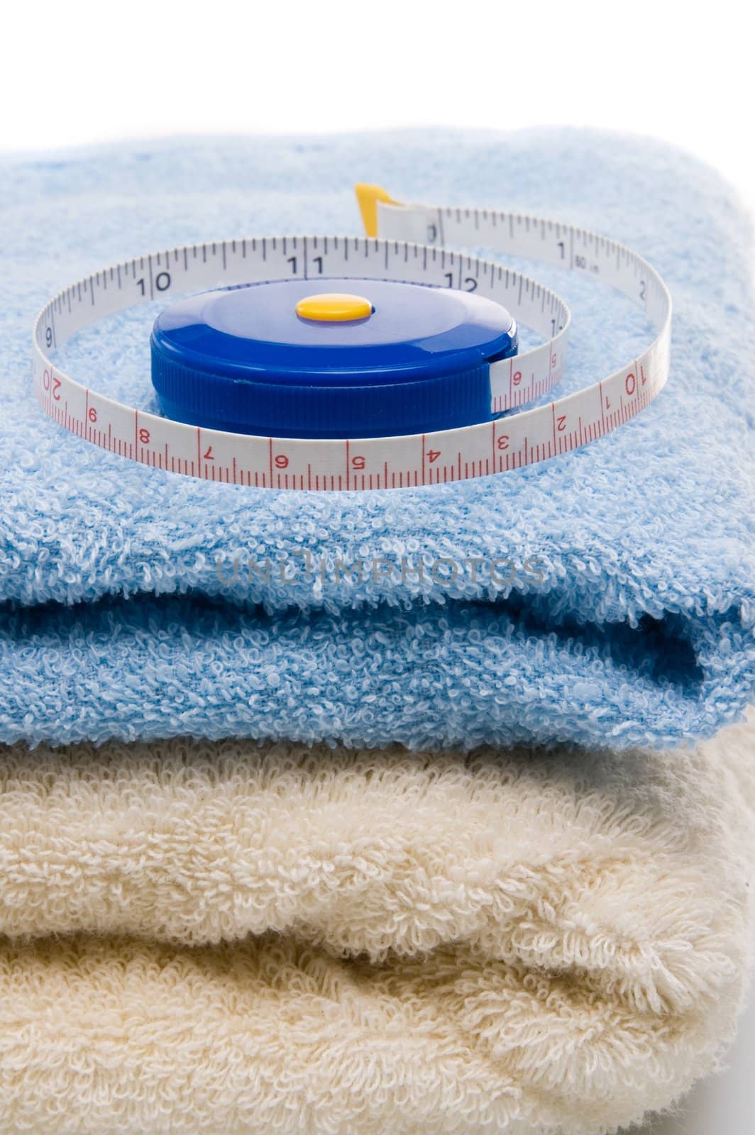Pile of towels and tape measure, white background