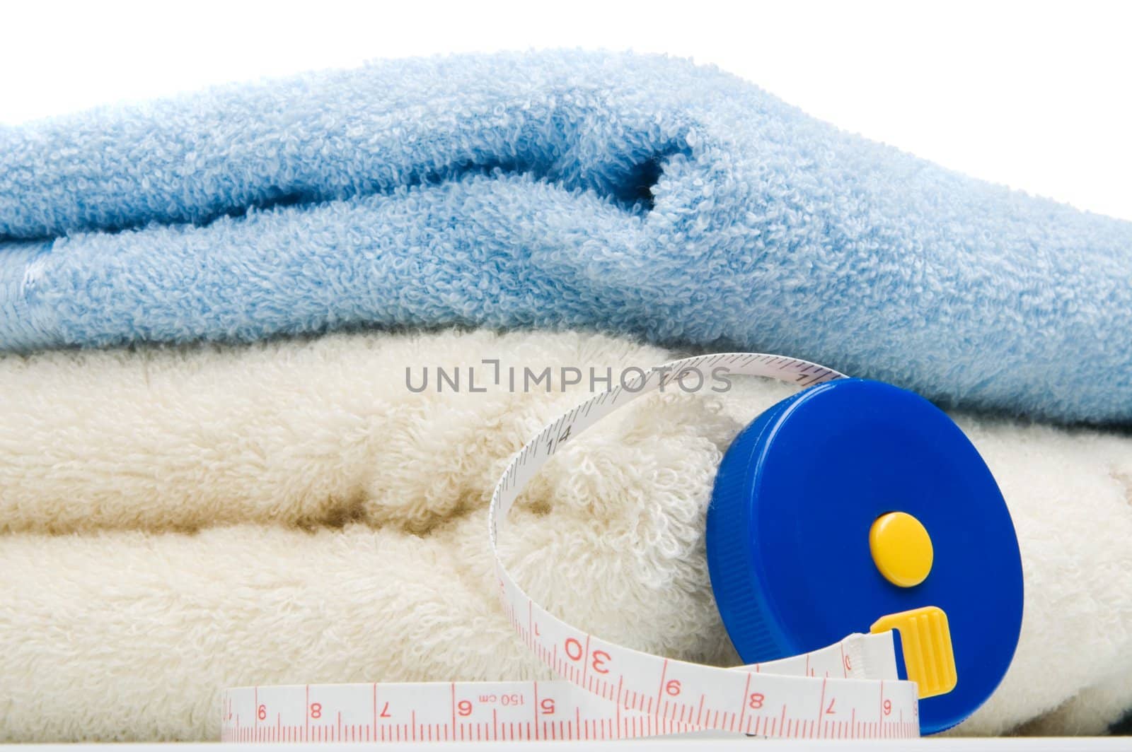 Pile of towels and tape measure, white background