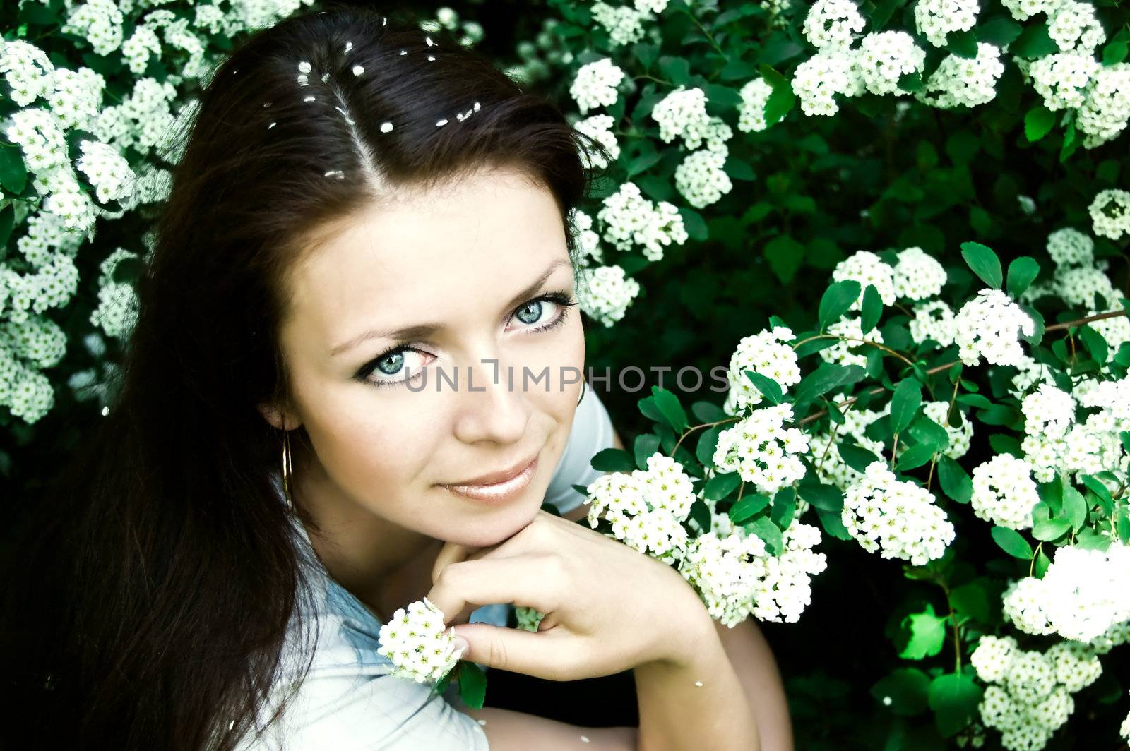 beautiful smiling girl among blooming spring blossom