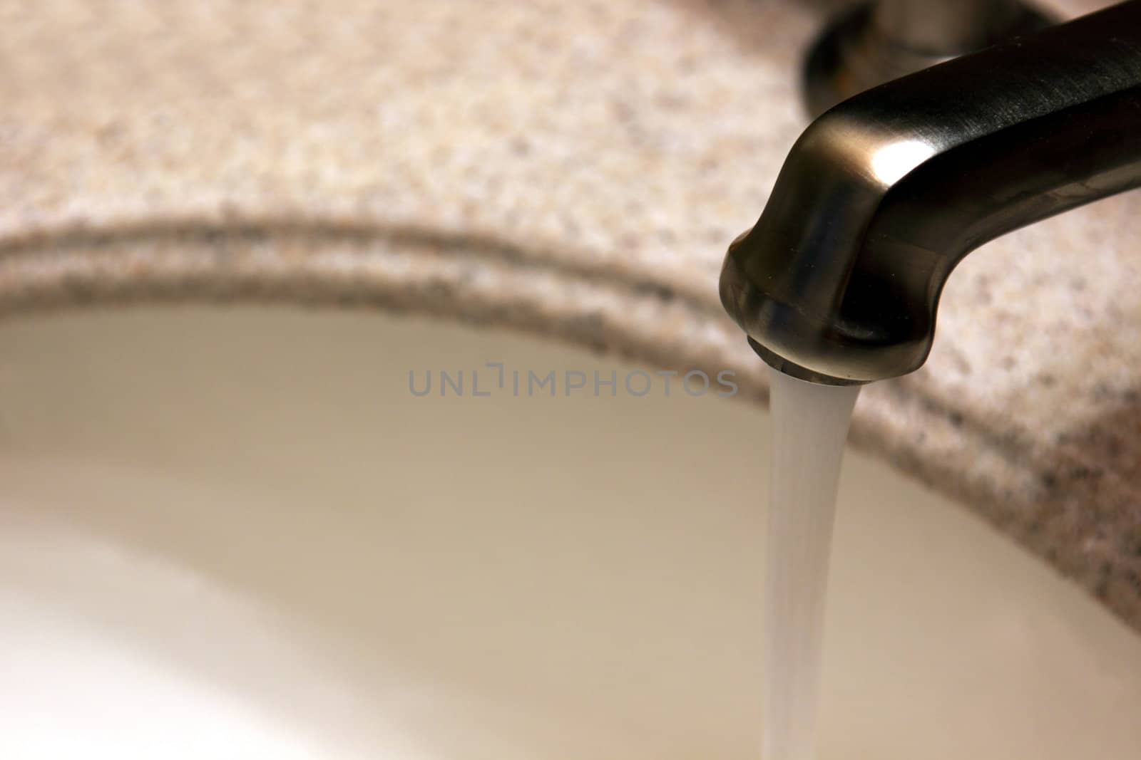 Water running out of a luxurious brushed metal faucet.