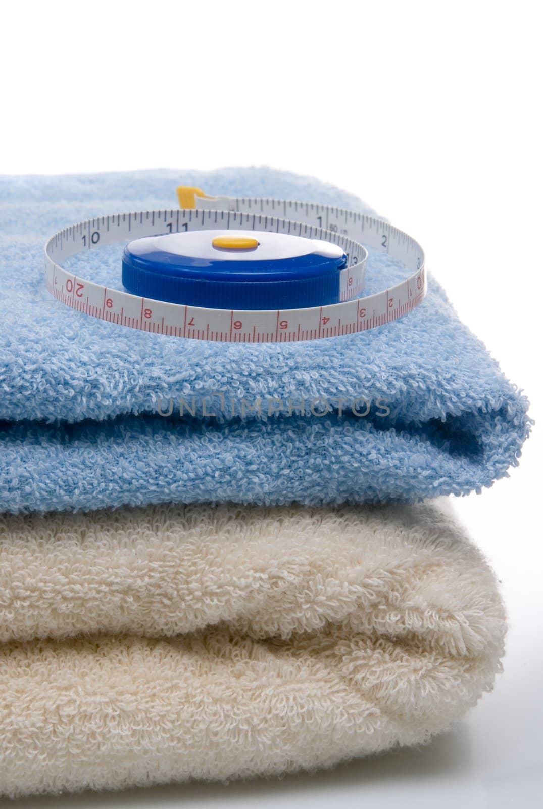 Pile of towels and tape measure, white background by Ravenestling