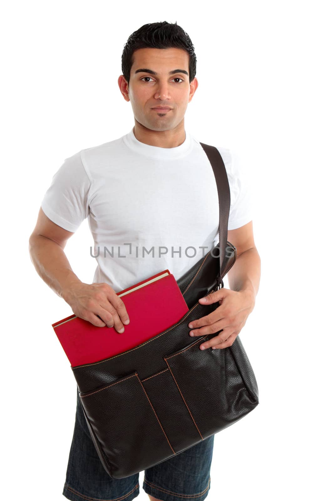 A casually dressed male placing a textbook into a leather satchel bag.  White background.