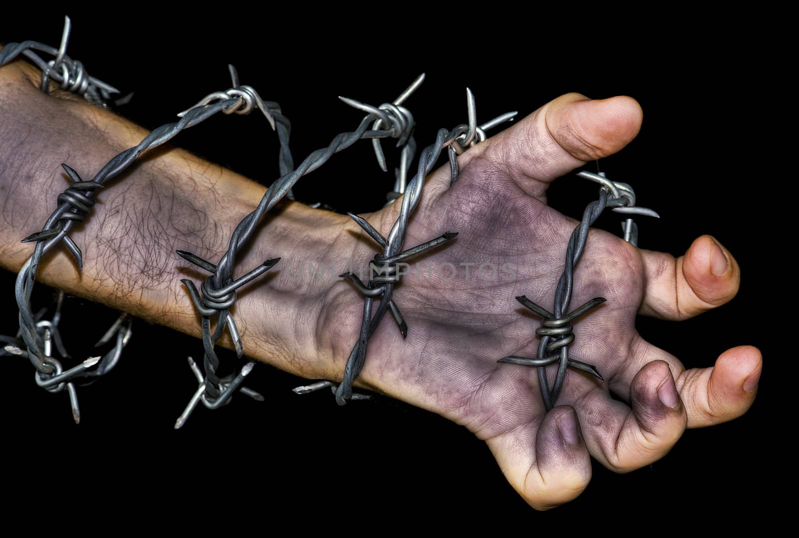 dirty hand grabbing a barbed wire on black background
