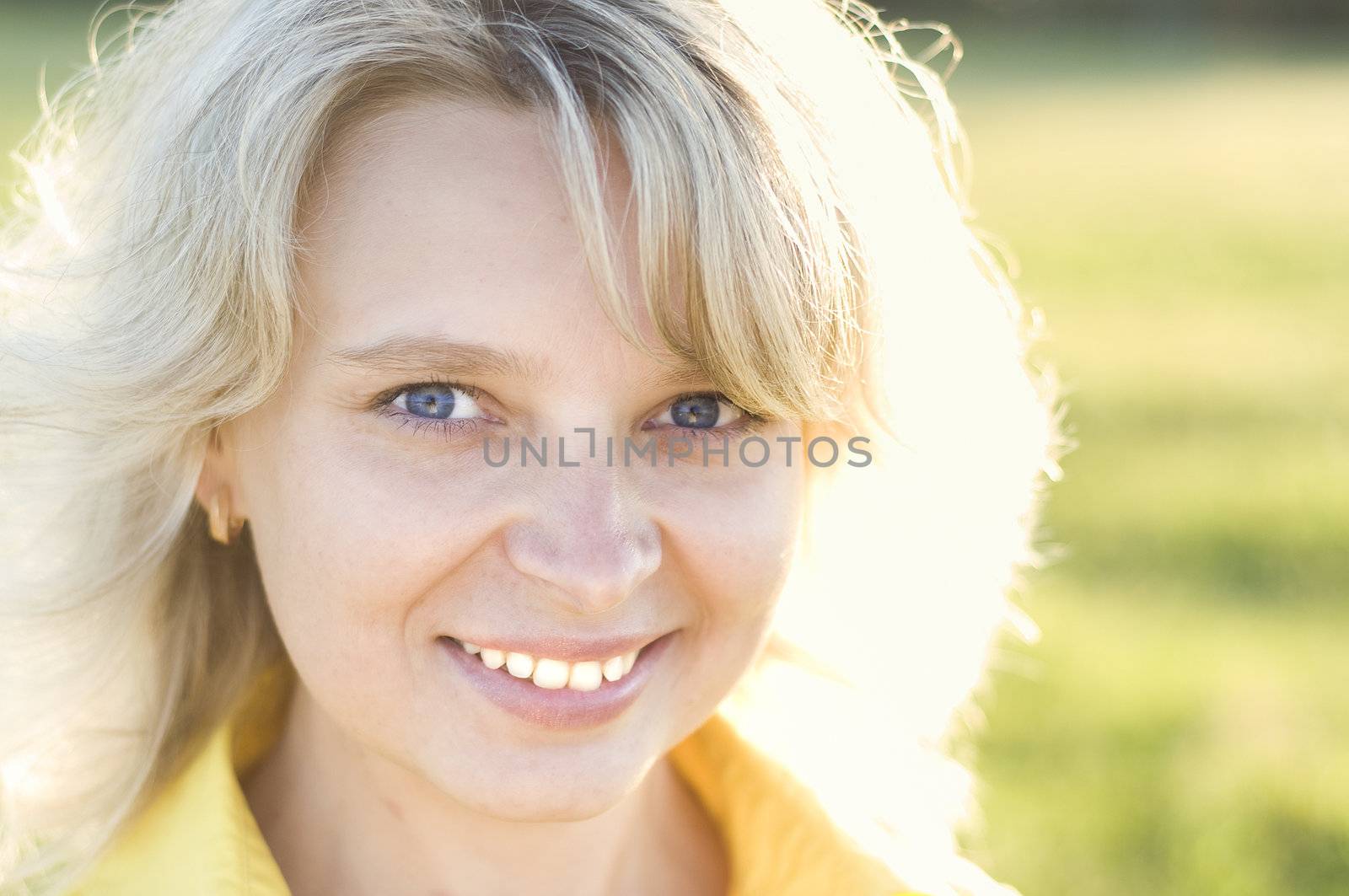 Portrait of smiling charming girl against summer green park