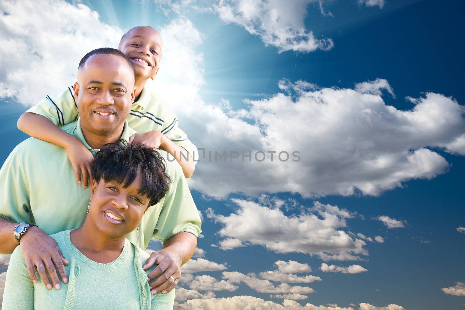 Happy African American Family Over Blue Sky, Sun Rays and Clouds.