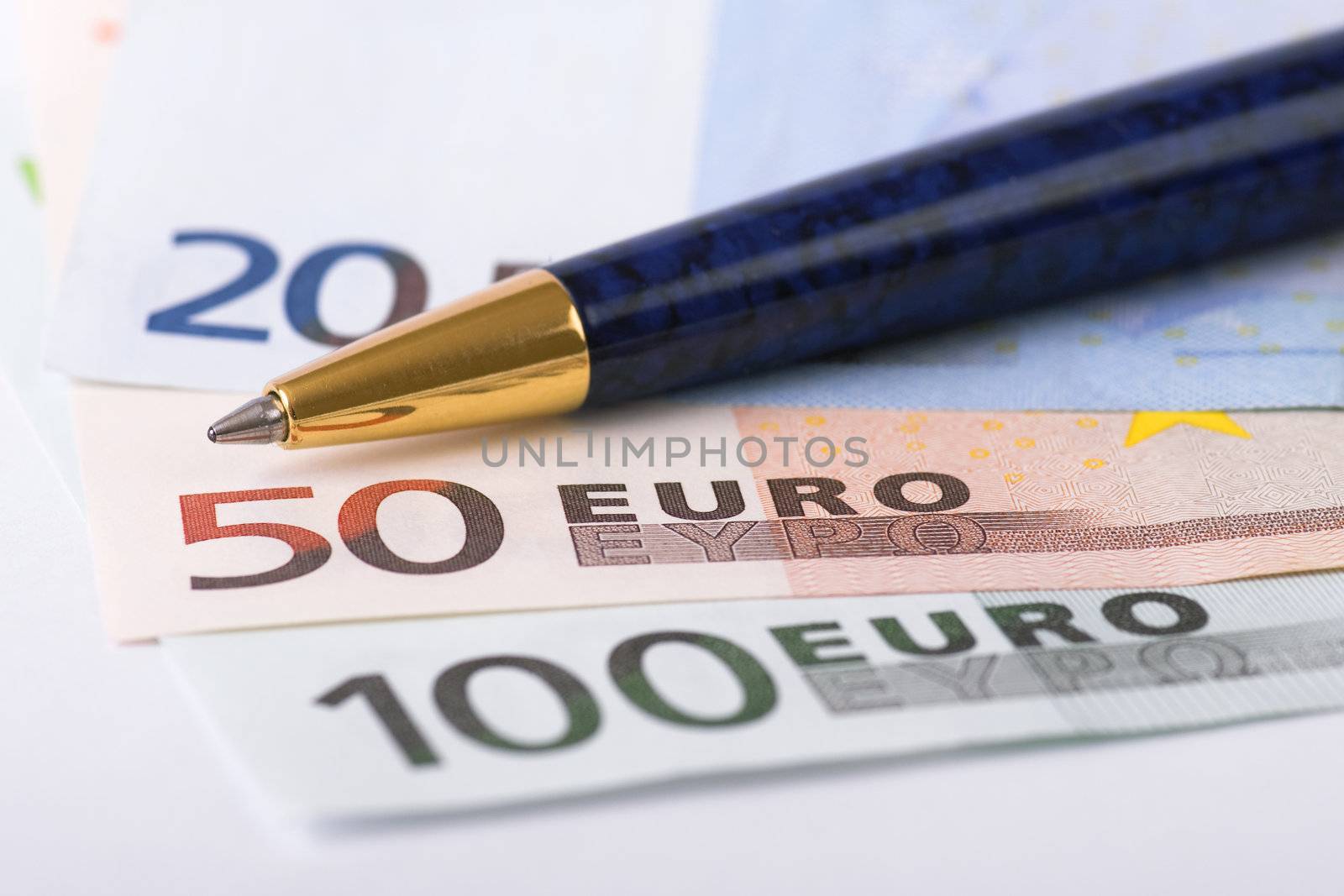 Euro banknotes and golden pen selective focus
