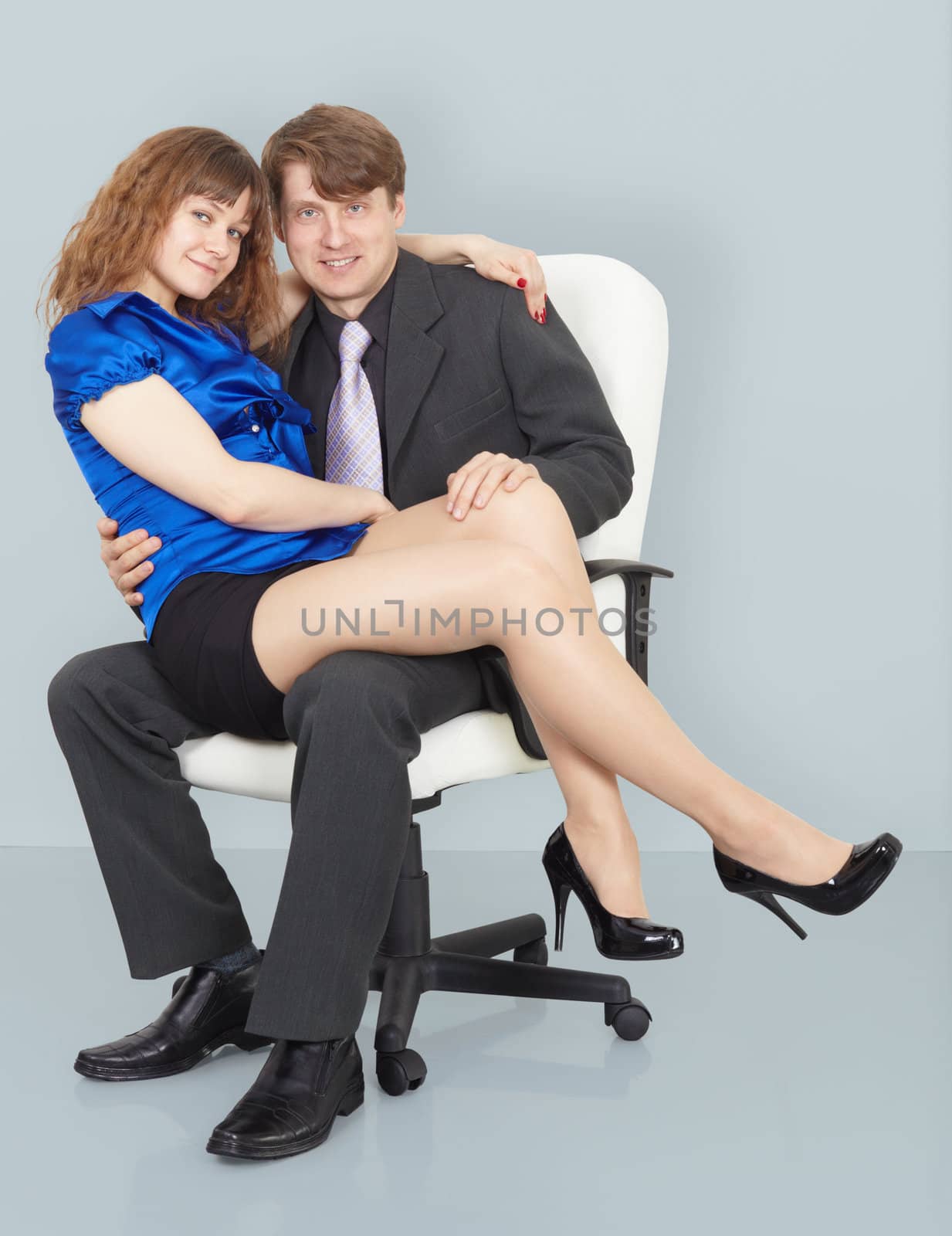 Young woman sitting on the lap of a man sitting in a chair
